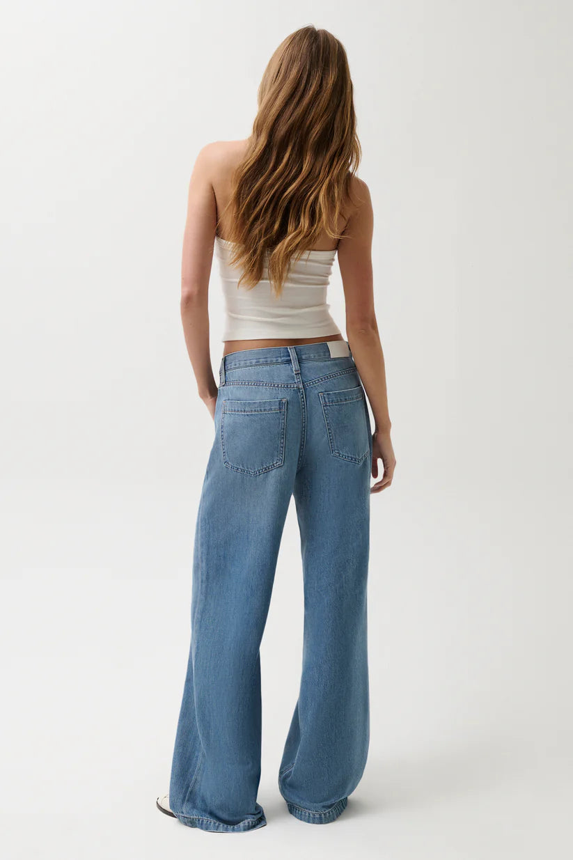Person wearing a white top and blue jeans on a plain background